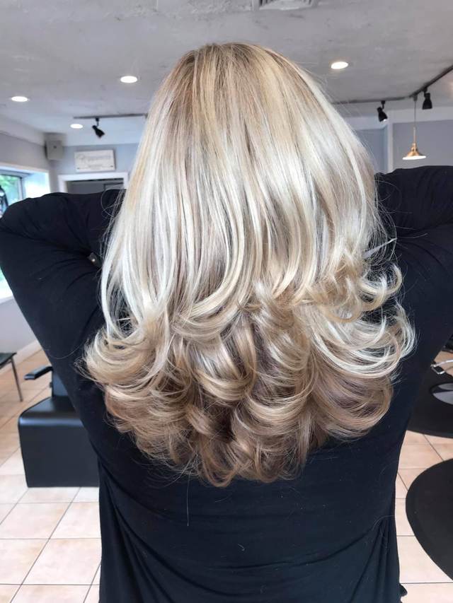 Back view of blonde hair with layered, curled ends