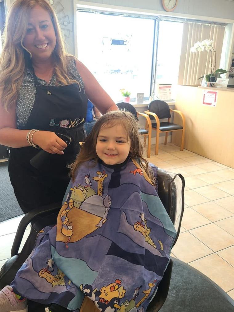 Marylou, founder of Euro Styles Salon, smiling beside a young client in a salon chair who is getting a haircut